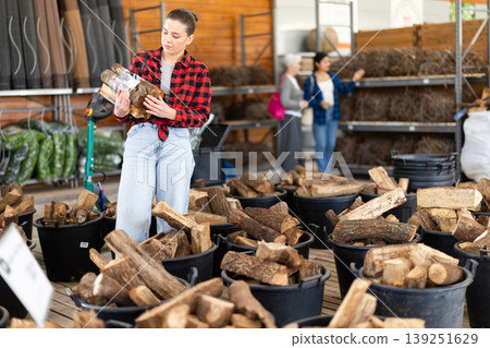 Young woman choosing firewood in store Young woman choosing firewood in store 139251629