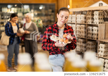 Girl selects and buys chicken eggs at grocery supermarket. 139251675