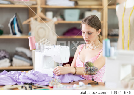 Young seamstress sews a dress on a machine 139251686