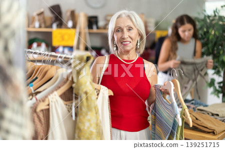 Positive mature woman choosing something for summer in clothing store Positive mature woman choosing something for summer in clothing store 139251715