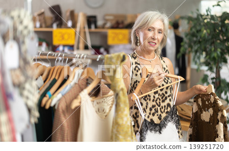 Positive mature woman choosing something for summer in clothing store Positive mature woman choosing something for summer in clothing store 139251720