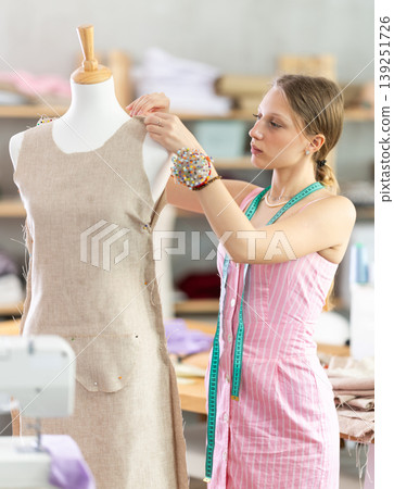Woman seamstress adjusts clothes on mannequin Woman seamstress adjusts clothes on mannequin 139251726