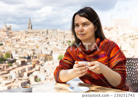 Portrait of a woman traveler sitting at a table and holding a cup of coffee Portrait of a woman traveler sitting at a table and holding a cup of coffee 139251743