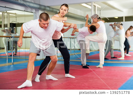Girl performing elbow strike and wristlock to man in self defence training 139251778