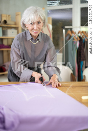 Mature dressmaker cutting fabric Mature dressmaker cutting fabric 139251795