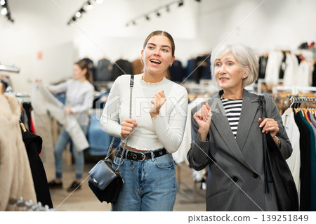 Two women customers watching large stock of clothes in clothing store Two women customers watching large stock of clothes in clothing store 139251849