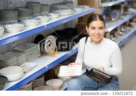 Young girl choosing square ceramic plates on shelves at Asian store Young girl choosing square ceramic plates on shelves at Asian store 139251872