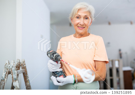 Mature woman posing with home renovation tools Mature woman posing with home renovation tools 139251895