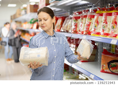 Interested woman reading label on packages of Asian noodles in supermarket Interested woman reading label on packages of Asian noodles in supermarket 139251943
