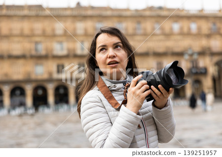 Woman standing on Placa Mayor in Salamanca and using her camera Woman standing on Placa Mayor in Salamanca and using her camera 139251957