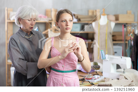 Mature tailoress measuring female client in sewing workshop 139251960
