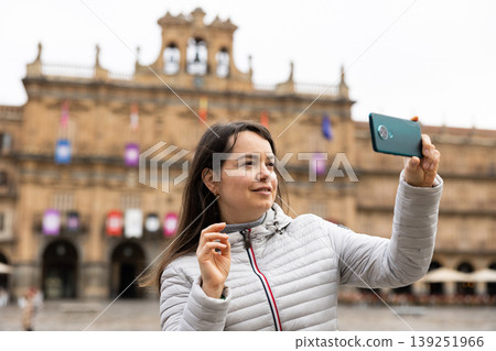 Woman is taking photos on her camera while journey through the Plaza Mayor. Spain Woman is taking photos on her camera while journey through the Plaza Mayor. Spain 139251966