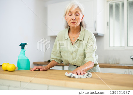 Elderly woman washing kitchen table during cleanup 139251987
