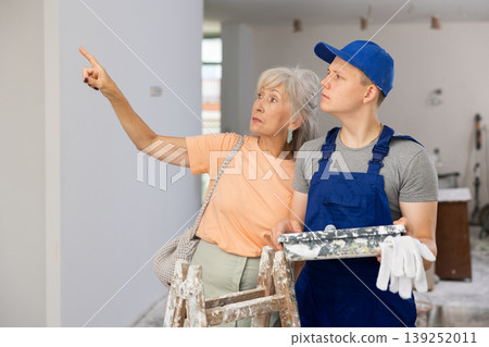 Senior woman discussing work details with teenager boy in constrcuction site 139252011