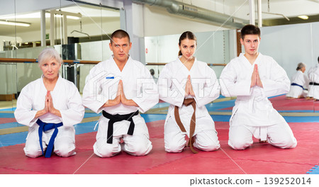 Men and women in kimono kneeling on floor in gym Men and women in kimono kneeling on floor in gym 139252014