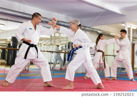 Elderly woman in kimono practicing martial arts techniques with trainer Elderly woman in kimono practicing martial arts techniques with trainer 139252023