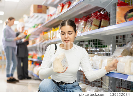 Positive young girl choosing noodles at Asian food store 139252084