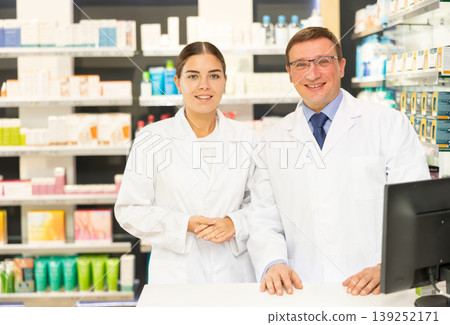 Young girl and middle-aged man pharmacists posing together in chemist's shop Young girl and middle-aged man pharmacists posing together in chemist's shop 139252171