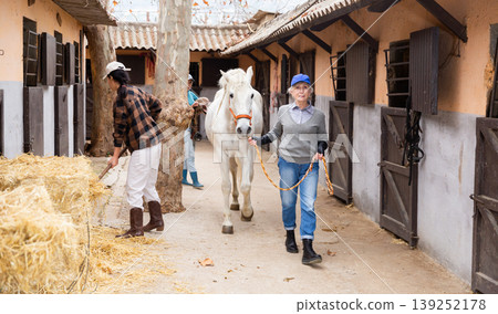 Women ranchers preparing white horse for ride Women ranchers preparing white horse for ride 139252178
