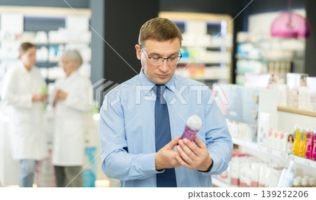 Man carefully selects intimate hygiene items or lubricant in pharmacy Man carefully selects intimate hygiene items or lubricant in pharmacy 139252206