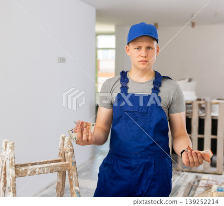 Discontented teenager with bunch of money he earned on first job in building site Discontented teenager with bunch of money he earned on first job in building site 139252214