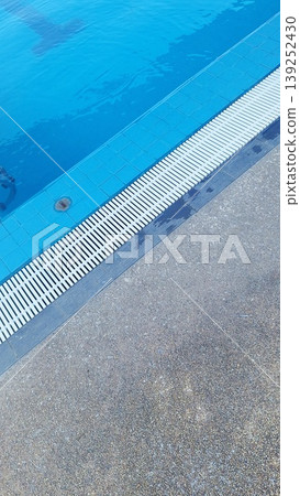 Close-up of swimming pool edge with white overflow drainage grating and non-slip floor 139252430