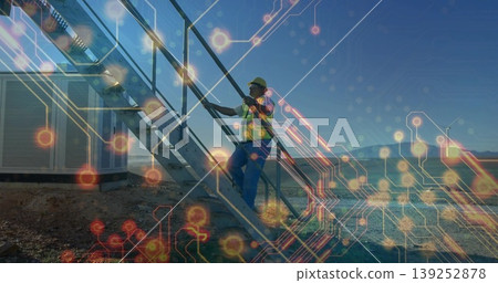 Technician climbing container stairs at wind farm, with helmet, vest, wind turbine, circuit overlay Technician climbing container stairs at wind farm, with helmet, vest, wind turbine, circuit overlay 139252878
