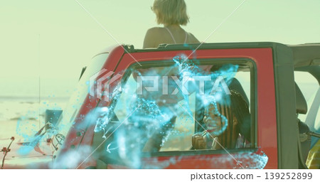 Two friends applying lipstick and gazing at ocean in red convertible on beach, under teal overlay Two friends applying lipstick and gazing at ocean in red convertible on beach, under teal overlay 139252899