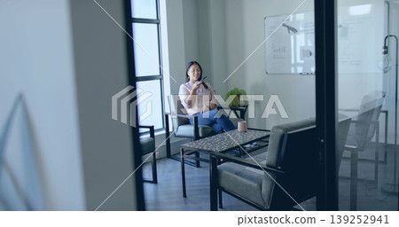 Talking businesswoman speaking into smartphone in meeting lounge, with ceramic mug, copy space Talking businesswoman speaking into smartphone in meeting lounge, with ceramic mug, copy space 139252941