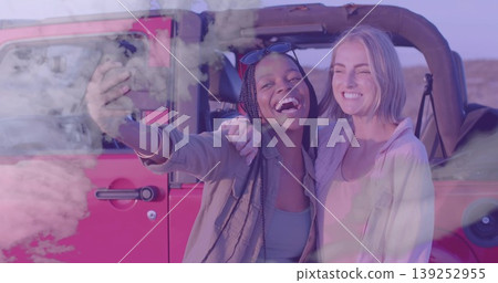 Taking selfie friends wearing sunglasses holding smartphone beside red off-road vehicle in desert Taking selfie friends wearing sunglasses holding smartphone beside red off-road vehicle in desert 139252955