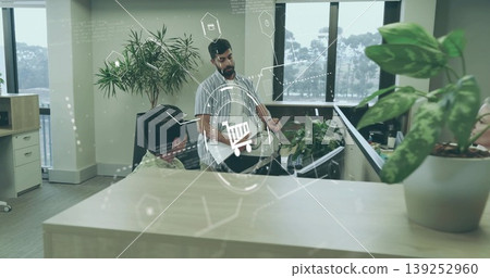 Discussing shopping cart overlay Asian man leaning on cubicle divider in office, with digital icons Discussing shopping cart overlay Asian man leaning on cubicle divider in office, with digital icons 139252960