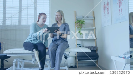 Prosthetic leg patient and therapist discussing exercise using tablet in clinic, with muscle charts Prosthetic leg patient and therapist discussing exercise using tablet in clinic, with muscle charts 139252970