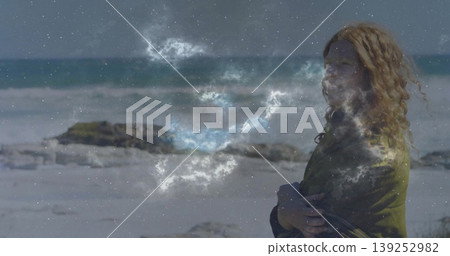 Standing woman crossing arms on beach, with olive jacket, red hair and nebula overlay, copy space Standing woman crossing arms on beach, with olive jacket, red hair and nebula overlay, copy space 139252982