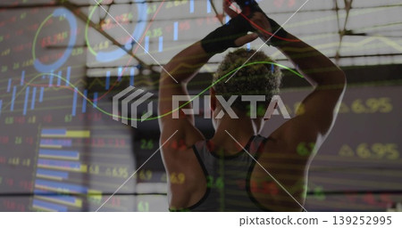 Raising athletic woman gripping overhead pull-up bar in gym, with overlaid stock market charts Raising athletic woman gripping overhead pull-up bar in gym, with overlaid stock market charts 139252995