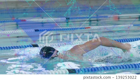 Swimming athlete performing front crawl in marked pool lane, with black swim cap and colored ropes Swimming athlete performing front crawl in marked pool lane, with black swim cap and colored ropes 139253022