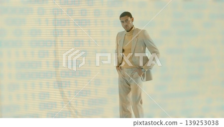 Man wearing beige suit standing in studio, with binary code projection and wristwatch, copy space Man wearing beige suit standing in studio, with binary code projection and wristwatch, copy space 139253038