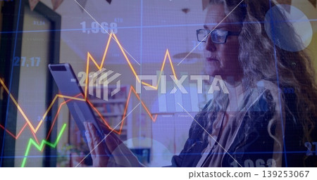 Reviewing businesswoman wearing blazer holding tablet in office with chart overlay, copy space Reviewing businesswoman wearing blazer holding tablet in office with chart overlay, copy space 139253067