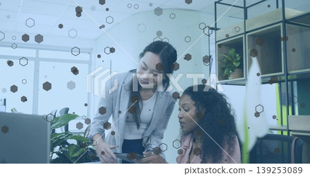Collaborating office professionals pointing at tablet and reviewing at desk, laptop stylus plant Collaborating office professionals pointing at tablet and reviewing at desk, laptop stylus plant 139253089
