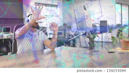 Gesturing using VR headset, man wearing striped shirt at open office desk with monitor, copy space Gesturing using VR headset, man wearing striped shirt at open office desk with monitor, copy space 139253094