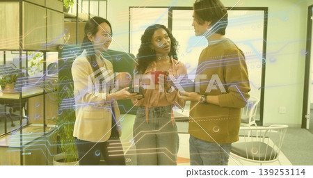 Discussing team holding smartphone and sipping red and dark mugs in office lounge with plants Discussing team holding smartphone and sipping red and dark mugs in office lounge with plants 139253114