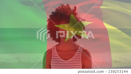 Standing male wearing white striped tank top on sunlit beach by ocean, with flag overlay graphic Standing male wearing white striped tank top on sunlit beach by ocean, with flag overlay graphic 139253144