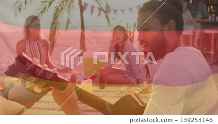 Friend strumming acoustic guitar on sandy beach platform at sunset, with cooler, drinks and snacks Friend strumming acoustic guitar on sandy beach platform at sunset, with cooler, drinks and snacks 139253146