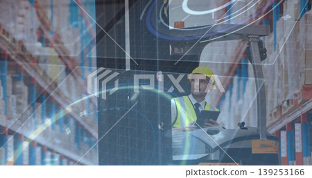 Forklift operator in hard hat and vest consulting tablet at warehouse controls, with racks of boxes Forklift operator in hard hat and vest consulting tablet at warehouse controls, with racks of boxes 139253166