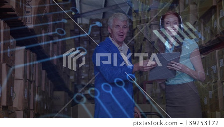Reviewing warehouse professionals consulting tablet in warehouse aisle, showing holographic overlay 139253172