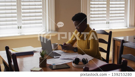 Holding smartphone woman in knit sweater working at dining table, with laptop papers, copy space Holding smartphone woman in knit sweater working at dining table, with laptop papers, copy space 139253280