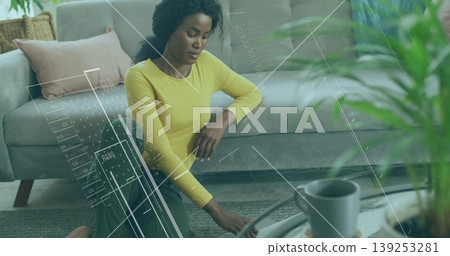 Adjusting Black woman in sportswear kneeling on living room rug by coffee table with yoga wheel Adjusting Black woman in sportswear kneeling on living room rug by coffee table with yoga wheel 139253281