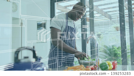 Slicing bell peppers on board, Black cook wearing striped apron in home kitchen, floating overlay 139253283