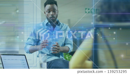 Gesturing African American businessman presenting network hologram in office with laptop and camera Gesturing African American businessman presenting network hologram in office with laptop and camera 139253295