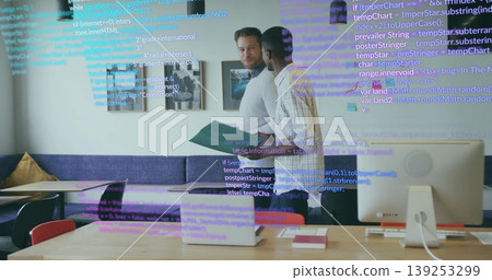 Discussing software tasks coworkers standing at table in office, with laptop and code overlay Discussing software tasks coworkers standing at table in office, with laptop and code overlay 139253299