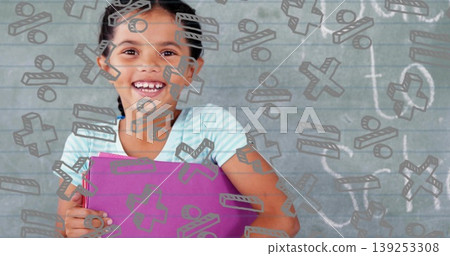 Smiling girl holding purple binder at school chalkboard, with digital math symbols, chalk drawings 139253308